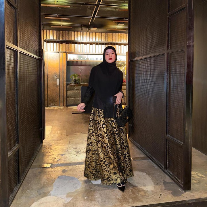 <p>Batik banyak digunakan sebagai busana pilihan untuk acara formal. Salah satu artis berhijab yang tampil memesona dengan hijab adalah Natasha Rizky. Ia mengenakan rok hitam bercorak batik warna emas. Ia memadukannya bersama hijab dan atasan serba hitam untuk tampilan glamor yang simpel.  (Foto: Instagram @natasharizkynew)</p>