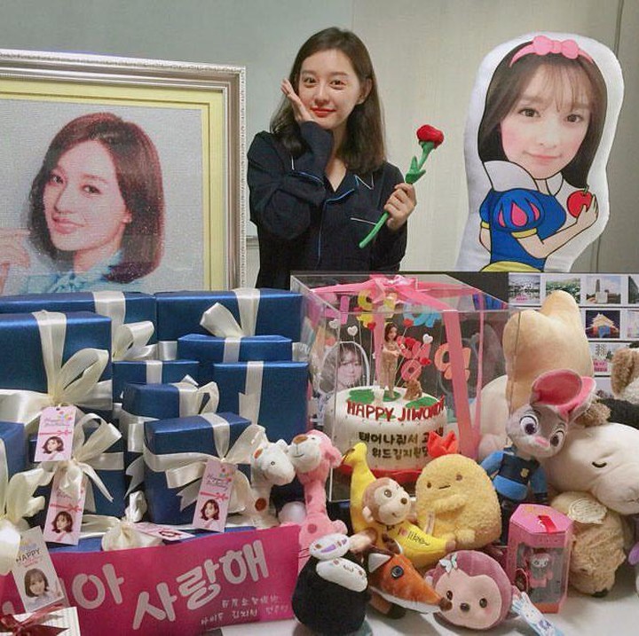 <p>Kim Ji Won berfoto dalam polesan <em>make-up</em> tipisnya bersama banyaknya hadiah lucu dari projek ulang tahun yang diadakan penggemarnya pada tahun 2016 lalu. Ia mengucapkan terima kasih atas ucapan dan hadiah yang diterimanya itu. (Foto: Instagram @geewonii)</p>