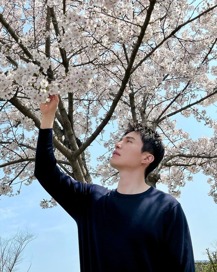 Pesona manusia fiksi Lee Dong Wook semakin hidup dalam potret baru yang dibagikannya ketika menyentuh kelembutan kelopak bunga. Kekontrasan suasana lembut alam dan gaya serba hitamnya membentuk harmoni indah./ Foto: instagram.com/leedongwook_official