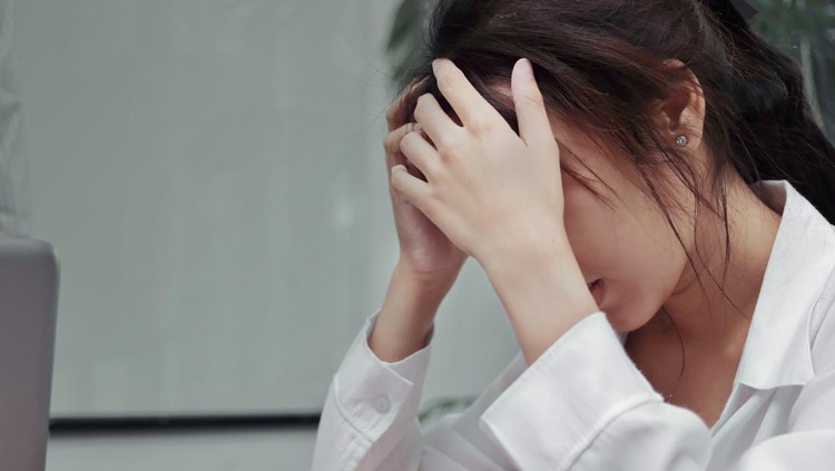 Stressed exhausted young Asian business woman suffering from severe depression in office.