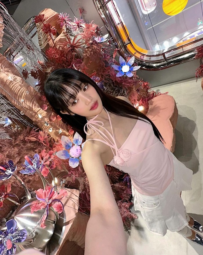 Minnie tampil mengesankan dengan atasan berwarna baby pink berhiaskan korsase yang feminin. Tidak hanya warna outfit yang membuanya tampil menonjol, namun aksen pita yang diikatkan di leher juga membuatnya lebih menarik./ Foto: Elle Korea
