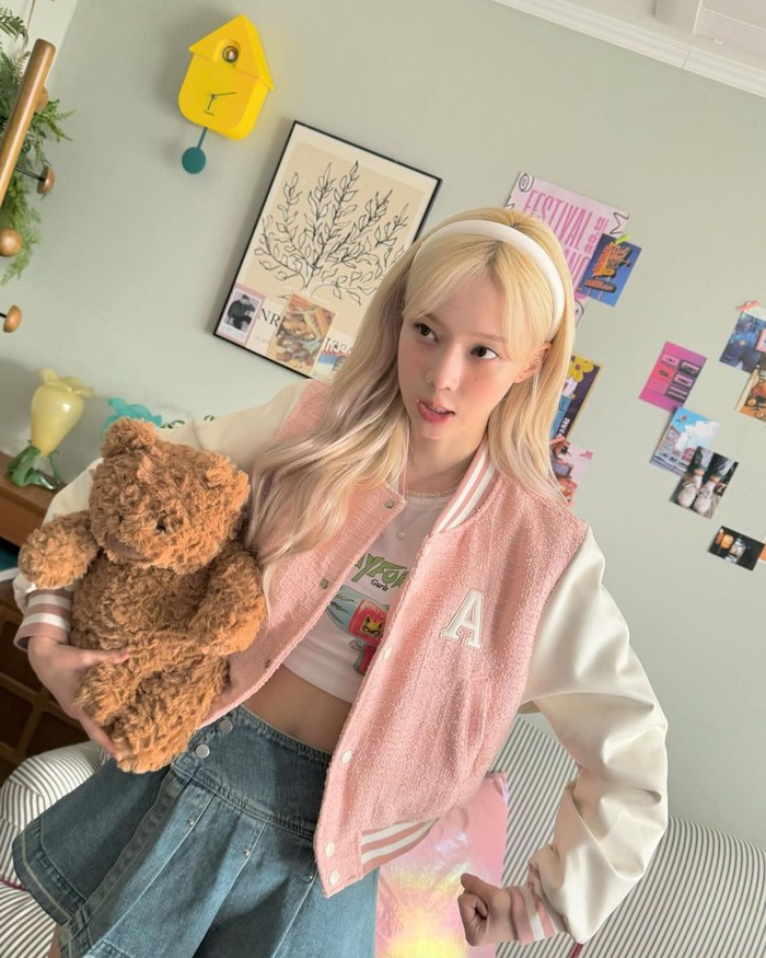 Winter mengenakan varsity jacket kasual berwarna baby pink yang lucu dan menggemaskan. Ia juga menambahkan riasan pipi merah muda yang serasi dengan tampilannya yang cute./ Foto: Elle Korea