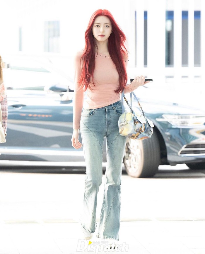 Yuna mencuri perhatian dengan kaus panjang berwarna baby pink yang memberikan sentuhan manis dan feminin. Rambut merahnya menambahkan nuansa dramatis dan menarik pada keseluruhan ensemble./ Foto: instagram.com/koreadispatch