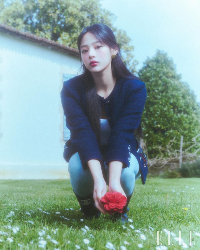 Minji merepresentasikan citra kamelia merah yang menjadi bunga paling dicintai di Paris dengan estetik. Visualnya yang lembut dan manis berpadu harmonis dengan alam hijau serta keindahan warna merah bunga di tangannya./ Foto: instagram.com/ellekorea