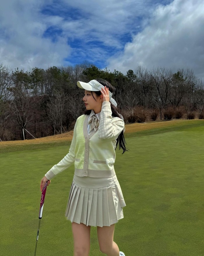 Jeong Ye In Lovelyz tampil menonjol dalam warna-warna pastel dengan memadukan kardigan kotak-kotak kuning dan rok lipit. Ia juga menambahkan pita di garis leher yang menarik perhatian./ Foto: Elle Korea