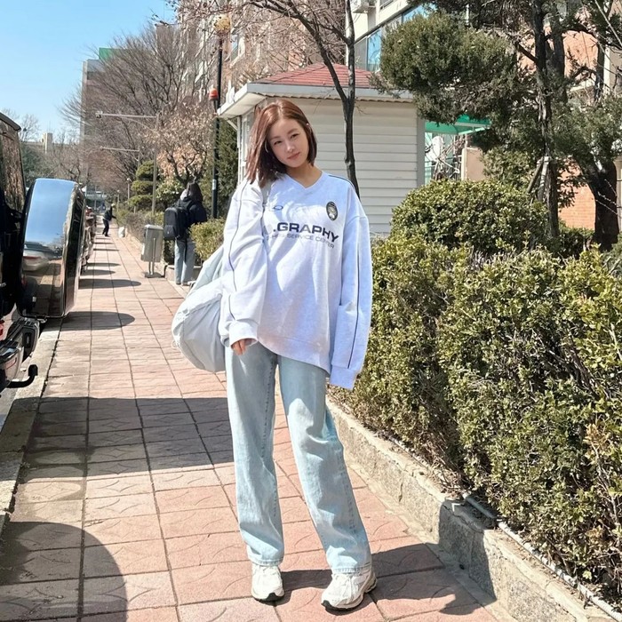 Perpaduan antara sweatshirt dan celana denim atau disebut juga dengan campus look menjadi outfit yang nyaman seperti yang dikenakan Kang So Ra. Ia memakai kaus siluet longgar, celana denim berwarna cerah, dan diakhiri dengan sepatu kets./ Foto: Elle Kore