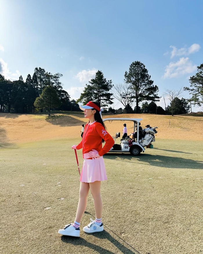 Uhm Ji Won yang menyukai berbagai olahraga tampil mencolok dengan outfit golf yang trendi. Ia memakai topi golf, kardigan, dan tongkat golf berwarna merah, yang dilengkapi dengan rok lipit serta sarung tangan berwarna pink yang match./ Foto: Elle Korea