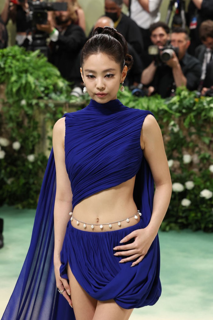 Kedua kalinya hadir di Met Gala, kali ini Jennie Kim memercayakan penampilannya pada Alaïa. Warna biru yang mencolok di tengah rona hijau, desain mini dress menyatukan cape dan train, rok drape asimetris, serta di-styling menggunakan belly chain. Gaun ini memakan waktu lebih dari 200 jam pengerjaan/ Foto: Getty Images/Marleen Moise
