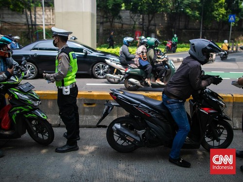Petugas kepolisian melakukan menindak tilang manual kepada pengendara yang memasuki jalur transjakarta di kawasan Gatot Subroto, Jakarta, Rabu (8/5/2024). (CNN Indonesia/Adi Ibrahim)