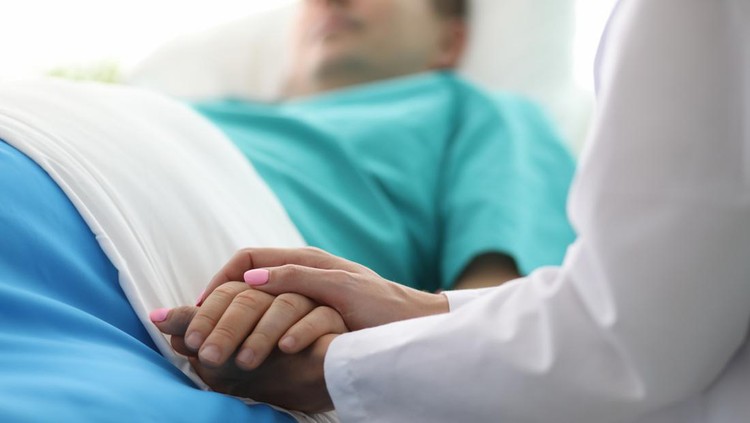 pasien koma In the Hospital Sick Male Patient Sleeps on the Bed. Heart Rate Monitor Equipment is on His Finger.