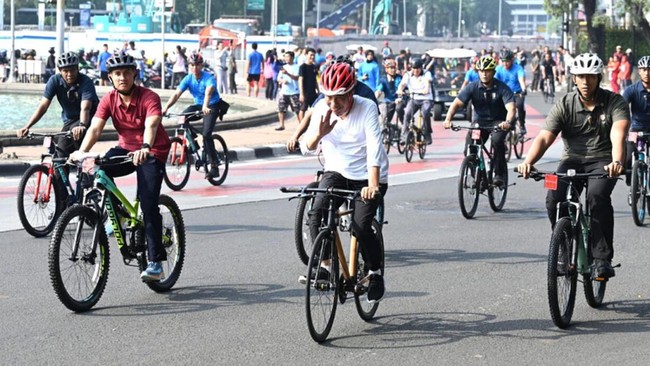 Presiden Jokowi mengayuh sepeda kayu saat car free day di area Sudirman-Thamrin, Jakarta, Minggu (12/5) pagi. Dia mengenakan helm warna merah.