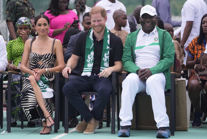 Prince Harry, left, and Meghan, right, holding hands upon arrival at the government house in Lagos Nigeria, Sunday, May 12, 2024. Prince Harry and his wife Meghan are in Nigeria to champion the Invictus Games, which Prince Harry founded to aid the rehabilitation of wounded and sick servicemembers and veterans. (AP Photo/Sunday Alamba) Meghan Markle Pakai Gaun Bernama Windsor Saat ke Nigeria