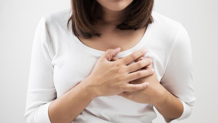 Woman hand checking lumps on her breast for signs of breast cancer on white background. Healthcare concept. Cancer self check; healthy girl.