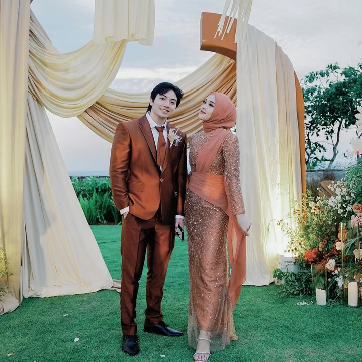 <p>Terakhir, yakni outift saat hadir di resepsi kedua yang berlangsung di Bali. Dalam acara tersebut, Putri mengenakan kebaya dengan model berbeda dari sebelumnya. Kali ini, ia tampil menawan dengan kebaya berwarna oranye yang dilapisi payet penuh dari atas hingga bawah. Outfit Putri juga dilengkapi selendang yang mengikat bahu hingga pinggang serta hijab berwarna senada. Bagaimana menurut pendapat Bunda? (Foto: Instagram @putridelinaa)</p>