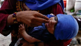 A mother uses her fingers to give water drops to her child during a hot summer day as a heatwave continues, in Jacobabad, Pakistan May 24, 2024. REUTERS/Akhtar Soomro     TPX IMAGES OF THE DAY