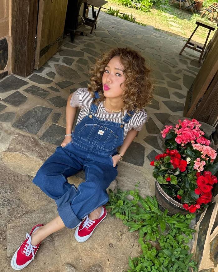 Mimi Oh My Girl memamerkan outfit jumpsuit overall bergaya retro yang unik dan chic. Ia memadukan tampilannya dengan baju garis-garis dan sepatu merah untuk menciptakan look yang menonjol./ Foto: Elle Korea