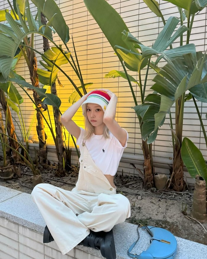 Winter dengan trendy menciptakan outfit jumpsuit overall putih dengan kaos cropped. Ia menambahkan sepatu bot hitam dan rambut yang ditata perm hippie yang cute dan kece./ Foto: Elle Korea