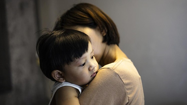 Mother carries the child in her arms. Little boy lies in his mother's shoulder. Sad son hugs mom.