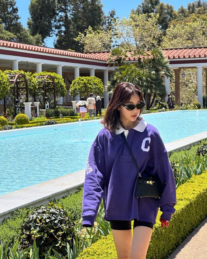 Ki Eun Se menambahkan suasana sporty dan retro dengan memadukan kemeja rugby berwarna ungu oversize dan celana pendek biker. Ia menambahkan kacamata hitam sebagai pengganti topi bola untuk tampilan yang menonjol dan stylish. / Foto: Elle Korea