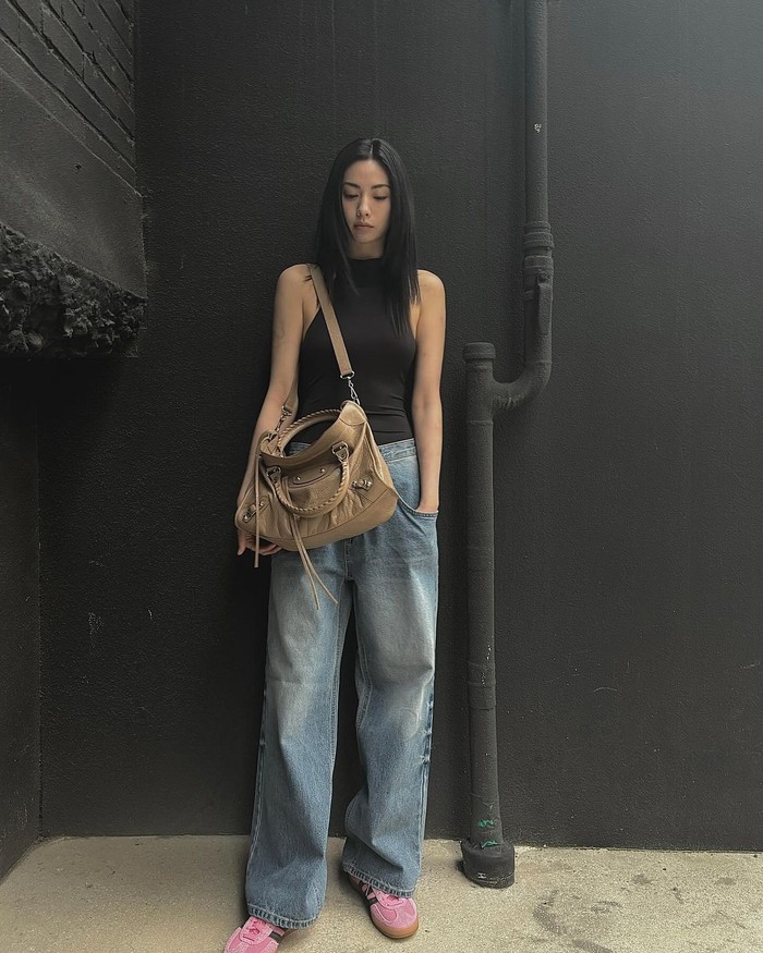 Nana mengenakan atasan halterneck hitam dengan garis bahu dalam dan celana denim bersiluet longgar. Meski perpaduan dua item tersebut minimalis, namun ia berhasil menciptakan suasana dramatis berkat penyesuaian kekuatan siluet./ Foto: Elle Korea