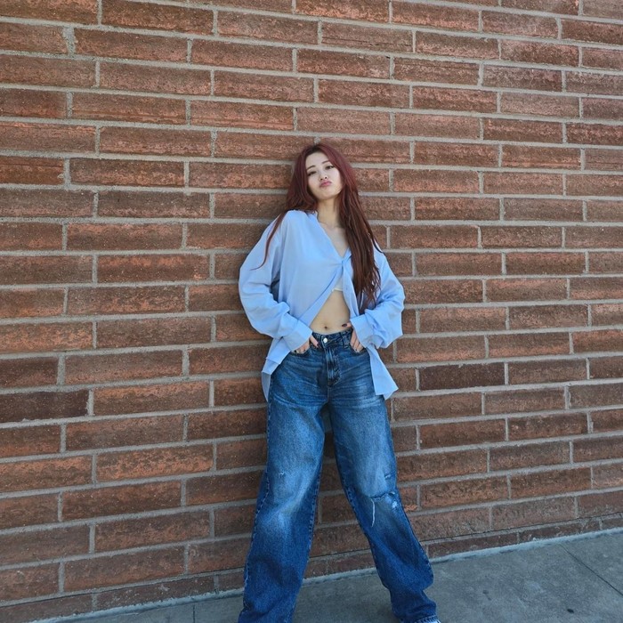 Yunjin LE SSERAFIM memilih celana denim dengan detail ripped untuk menonjolkan suasana wild. Ia juga menonjolkan siluet oversized dengan memakainya seolah-olah disampirkan di pinggul./ Foto: Elle Korea