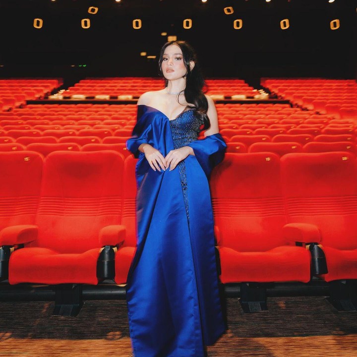 <p>Di gala premier filmnya, Davina mengenakan gaun bahu terbuka berwarna biru tua. Riasan wajahnya tampak elegan dengan gaya rambut panjang yang dikuncir setengah. (Foto: Instagram @davinaakaramoy)</p>