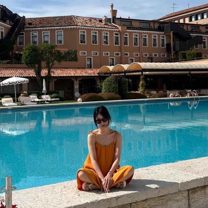 <p>Kali ini outfit Song Hye Kyo cocok untuk bersantai saat sedang berada di hotel. Song Hye Kyo terlihat sedang duduk di pinggir kolam renang mengenakan spaghetti-strap dress berwarna tangerine. (Foto: Instagram @kyo1122)</p>