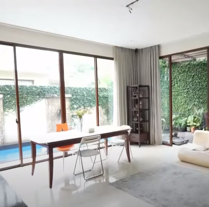 <p>Sudut lain yang juga cukup unik adalah ruang makan keluarga. Ruang makan ini hanya berisi meja dan kursi makan, serta sebuah sofa. Ruang makan ini terlihat begitu cerah dan estetik karena menghadap langsung ke kolam renang. (Foto: YouTube TRANS7 OFFICIAL)</p>