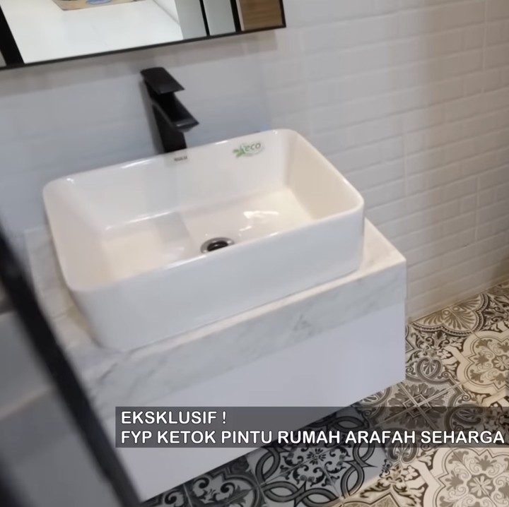 <p>Sudut lain yang ditunjukkan Arafah adalah kamar mandi berukuran kecil. Meski terbilang sempit, kamar mandi ini didesain elegan dengan dominasi keramik putih, serta dilengkapi oleh wastafel plus cermin, shower, dan toilet duduk. (Foto: YouTube @TRANS7 OFFICIAL)</p>