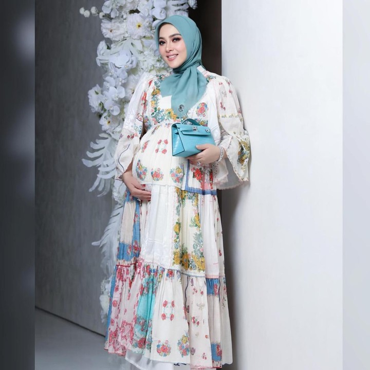 <p>Syahrini tampil lebih <em>glam</em> dengan <em>pleated dress</em> yang dihiasi dengan padu padan motif <em>floral</em> beraneka warna. Tampilan itu dilengkapi dengan hijab warna toska yang senada dengan <em>handbag</em> mungil di tangannya.  (Foto: Instagram @princessyahrini)</p>