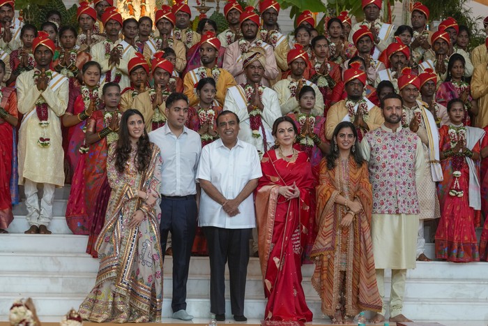 Chairman of Reliance Industries Limited Mukesh Ambani, third from left, poses for a photograph with his family members and underprivileged couples during a mass wedding organized by him as the part of pre-wedding celebrations of his youngest son, Anant Ambani, in Navi Mumbai, India, Tuesday, July 2, 2024. (AP Photo/Rafiq Maqbool)