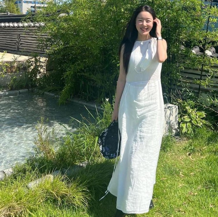 <p>Han Sunhwa kerap menggunakan <em>long dress</em> yang menambah kecantikannya yang terkesan lugu. Seperti di potret satu ini, Han Sunhwa memilih gaun putih panjang dengan aksesori topi untuk menemaninya berjalan-jalan di musim panas. (Foto: Instagram @shh_daily)</p>