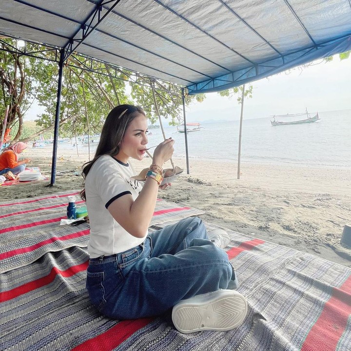 <p>Sembari menunggu suami dan anak-anaknya bermain, Momo menyantap makanan yang telah disajikan di pinggir pantai. "Diajakin berhenti makan di tempat main papanya Briell Abe semasa kecil dulu," tulisnya. (Foto: Instagram@therealmomogeisha)</p>