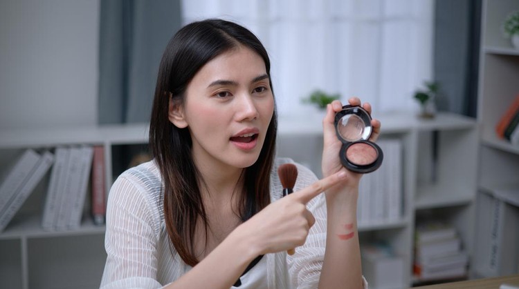 Portrait of Beautiful young Asian woman blogger shows how to make up and use cosmetics at home. Business online, cosmetic and influencer marketing concepts.