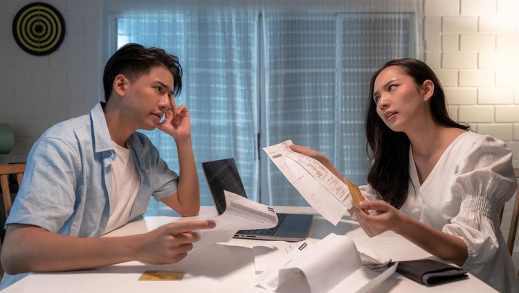 Stressed Asian couple fighting over unpaid debts.
