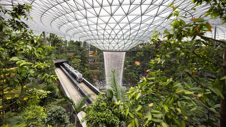 Arsitektur Jewel Changi Airport Singapura Singapore - January 7, 2024: Singapore Jewel Changi Airport. The Singapore Jewel Rain Vortex is the largest indoor waterfall in the world located inside the Jewal Changi Airport in Singapore. Singapore Airport Monorail train driving through the huge Jewel Changi.