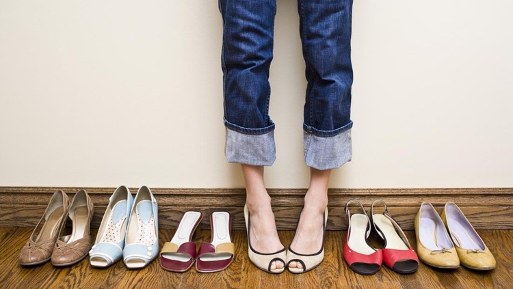 Woman stands in a pair of open toe heels in the middle of a row of shoes showing the concepts of consumerism, individuality, shoe addiction, fashion and shopping
