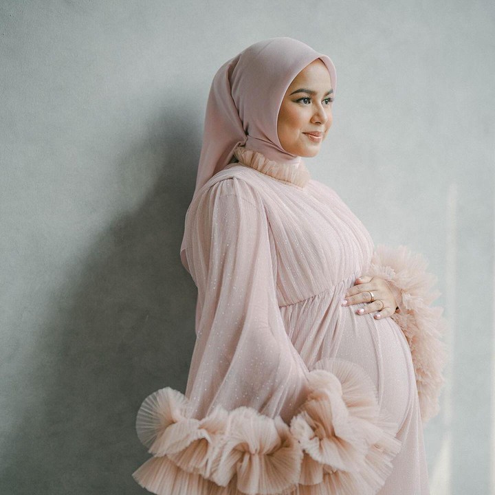 <p>Di foto lainnya, Dila terlihat mengenakan gaun berwarna merah muda kecokelatan yang juga senada dengan warna penutup kepalanya. Gaun cantik ini menonjolkan <em>baby bump</em> kehamilan Dila yang sudah besar. (Foto: Instagram @asrifaradila)</p>