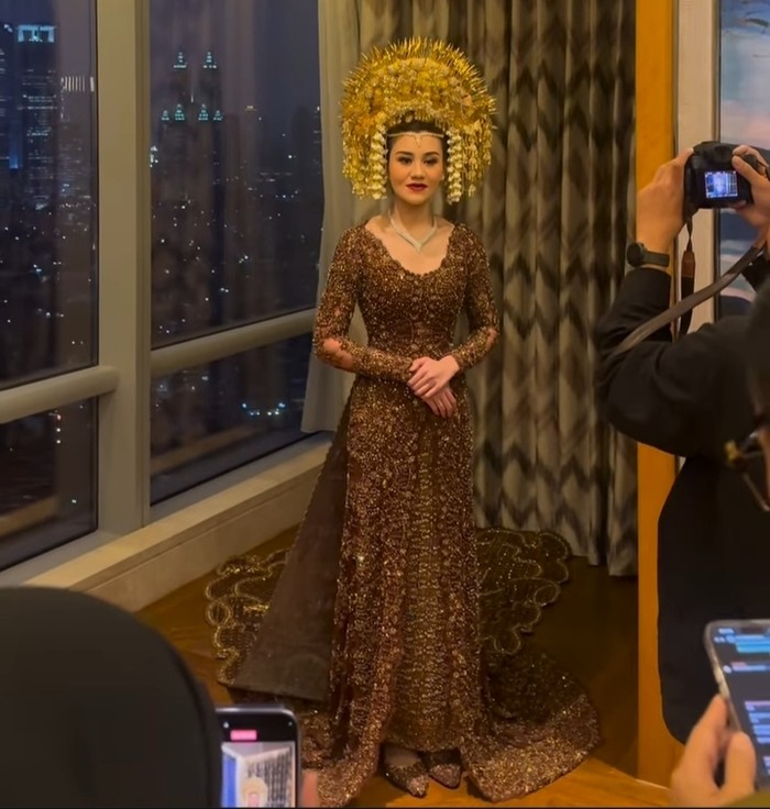 Aaliyah memakai kebaya coklat rancangan Penny Arie R dari Studio BOH. Detail kebaya resepsinya hampir mirip seperti kebaya akad dengan ekor menjuntai dan terbelah. (Aaliyah Massaid/Foto:instagram.com/desiskandarwedding)