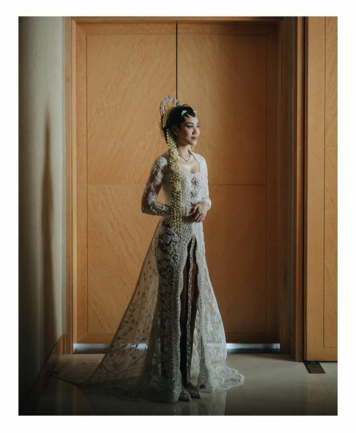 Kebaya brokat panjang berwarna putih yang dipakai oleh Aaliyah saat akad nikah merupakan rancangan dari Rika Wirtjes. Kebaya dengan sentuhan slit di bagian depan ini dipadukan rok batik berwarna cokelat. (Aaliyah Massaid/Foto:instagram.com/morden.co)