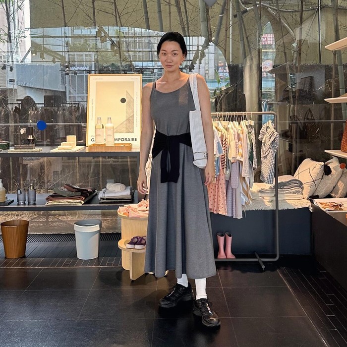 Jang Yun Ju memodifikasi outfit long dress dengan kardigan hitam yang dililitkan di pinggang. Ia melengkapinya dengan sepatu kets hitam, kaus kaki dan tas putih yang casual dan trendy. / Foto: Allure Korea