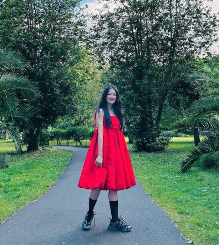 Kim Hye Yoon tampil cute dan playful dengan mengenakan cherry dress merah yang mencolok. Ia memadukannya dengan sneakers dan kaus kaki hitam untuk tampilan yang lebih berbeda dan tidak terlalu feminin. / Foto: Instagram/hye_yoon1110