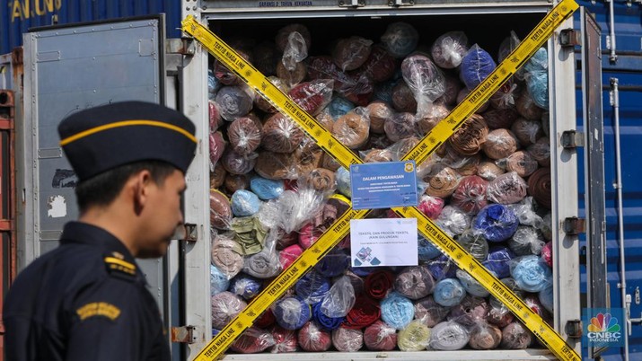 Petugas Bea Cukai berjaga disamping pakain bekas (balpres) di Tempat Penimbunan Pabean (TPP) Bea dan Cukai, Cikarang, Kabupaten Bekasi, Jawa Barat, Selasa (6/8/2024). (CNBC Indonesia/Faisal Rahman)