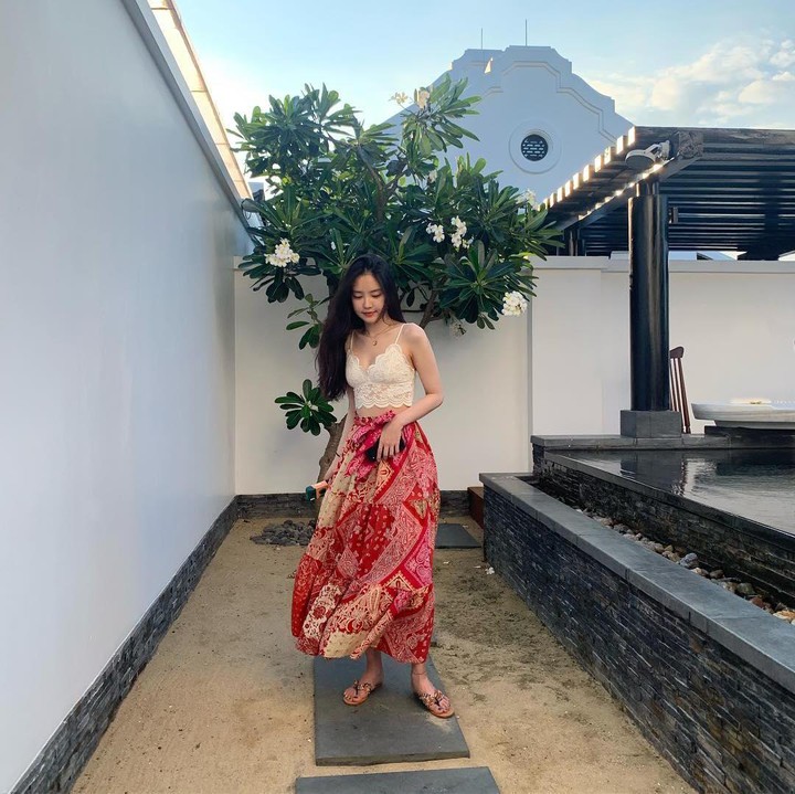 <p>Ketika berlibur di Vietnam, Son Naeun terlihat memesona dengan <em>lace crop top</em> yang dipadukan dengan rok bermotif etnik. Ia juga memakai sandal yang menambah sentuhan musim panas. (Foto: Instagram @marcellasne_)</p>