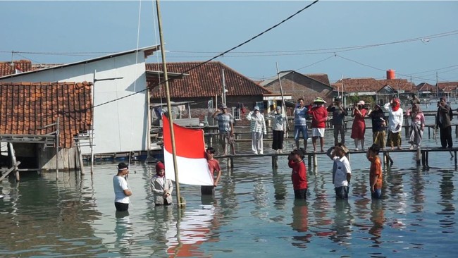 Sejumlah simpatisan dan warga salah satu dukuh pesisir Pantura Jawa yang 'tenggelam' melakukan upacara HUT ke-79 RI di kampung  yang sudah direndam air laut.