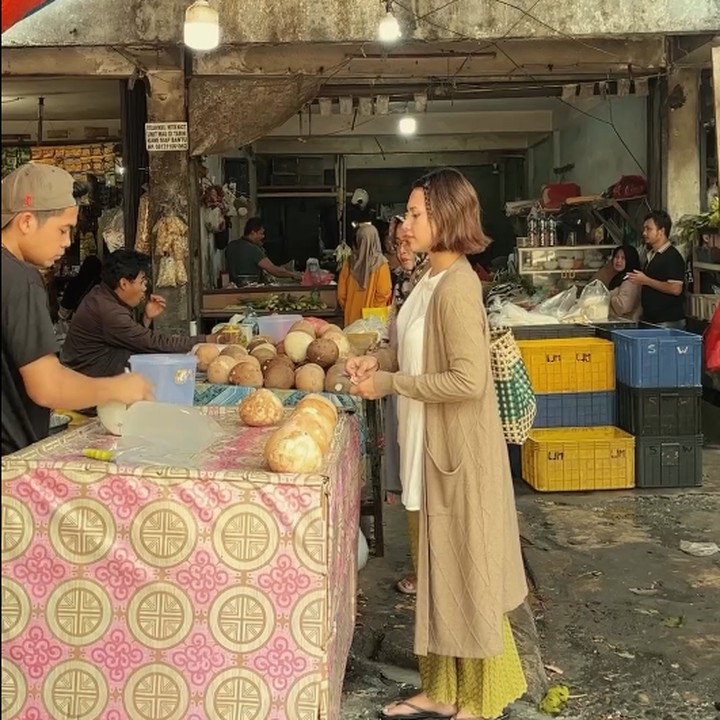 <p>Indah hanya mengenakan kaos dengan celana bahan, cardigan panjang berwarna cokelat, dan sendal saat berbelanja di pasar tradisional. Bunda satu anak ini juga tidak mengenakan riasan apa pun. (Foto: Instagram @indahpermatas)</p>