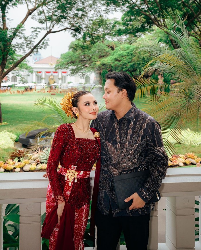 Mahalini dan Rizky Febian hadiri upacara HUT RI ke-79 di Istana Negara. Berbalut pakaian warna kontras, Rizky mengenakan kemeja batik hitam dan Mahalini totalitas dalam kebaya Bali kontemporer. Kebaya merah tersebut dilapisi payet senada, serta dipermanis obi yang disematkan bros emas/ Foto: Instagram.com/mahaliniraharja