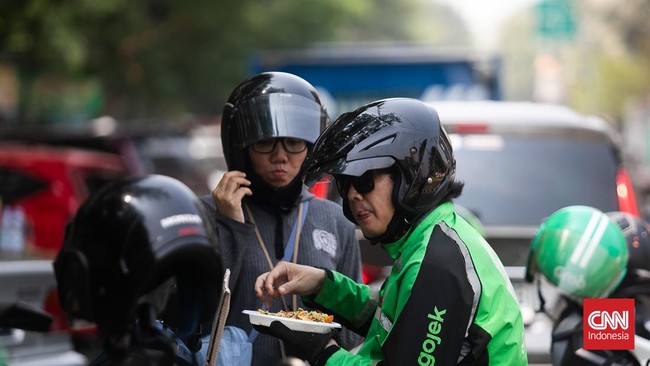 Warga dan para pengemudi ojek online menyantap makan siang gratis yang dibagikan Yayasan Damaris Pancasila Indonesia di Kawasan Kemayoran, Jakarta Pusat, Rabu (21/8/2024). (CNN Indonesia/ Adi Ibrahim)