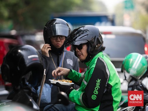 Warga dan para pengemudi ojek online menyantap makan siang gratis yang dibagikan Yayasan Damaris Pancasila Indonesia di Kawasan Kemayoran, Jakarta Pusat, Rabu (21/8/2024). (CNN Indonesia/ Adi Ibrahim)