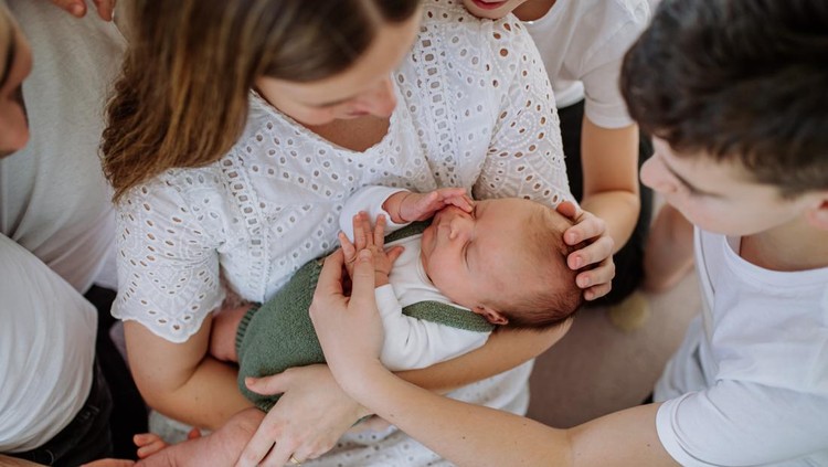 newborn Big family with four sons enjoying their newborn baby.